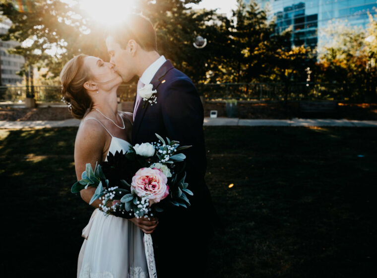 Couple kissing at sunset with shadowed trees behind