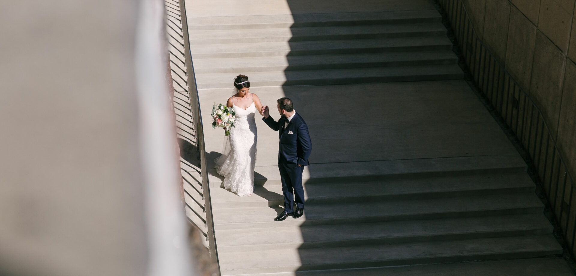 Wedding couple holding hands on concrete stairs