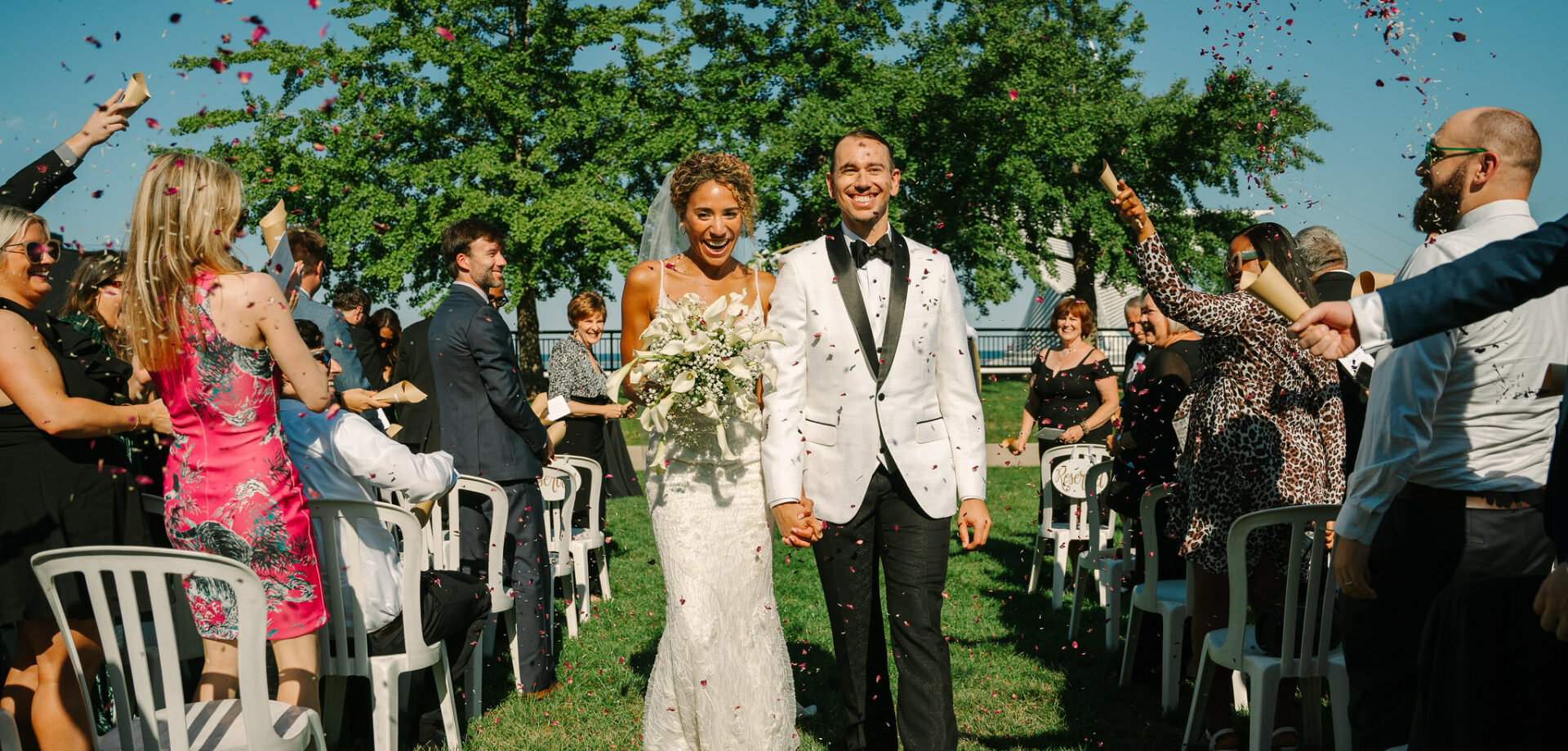 happy couple with guests throwing confetti