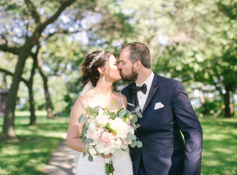 Wedding couple kissing with spring trees behind